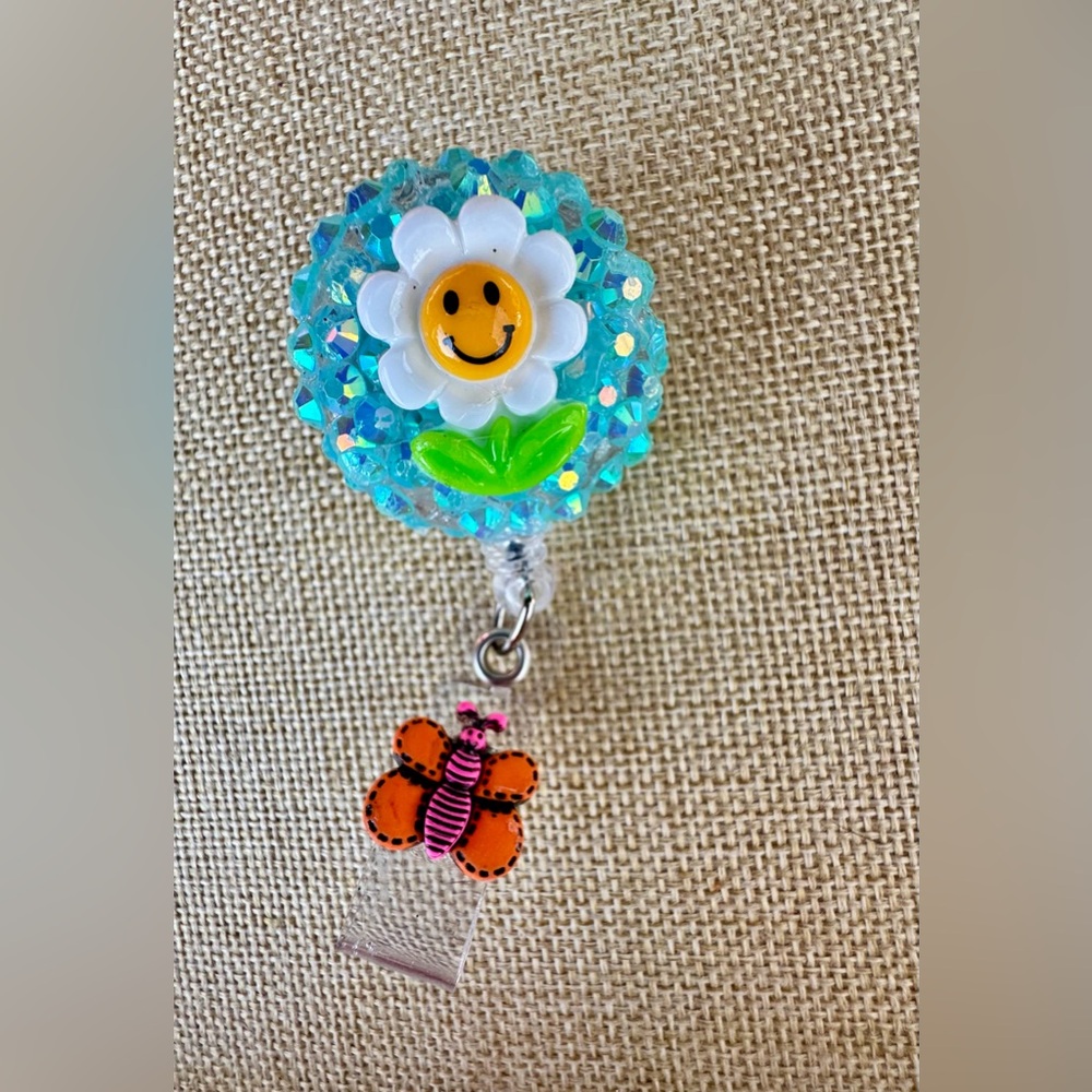 Smiling Daisy Glitter Badge Reel with Orange Butterfly Charm